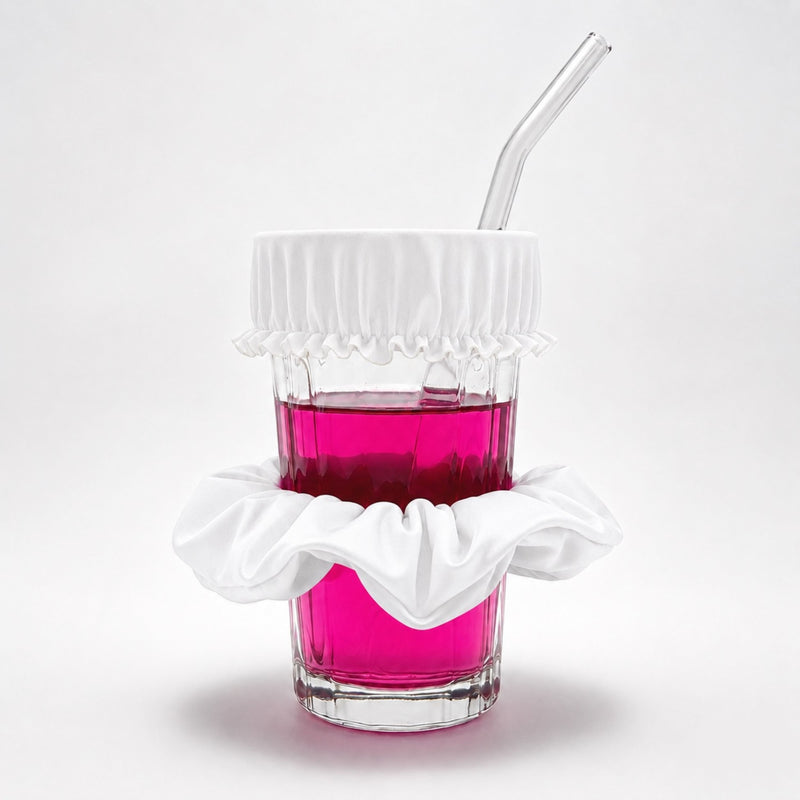 Chouchou anti-drogue rose bonbon Protect Your Glass déployé sur un verre avec paille.