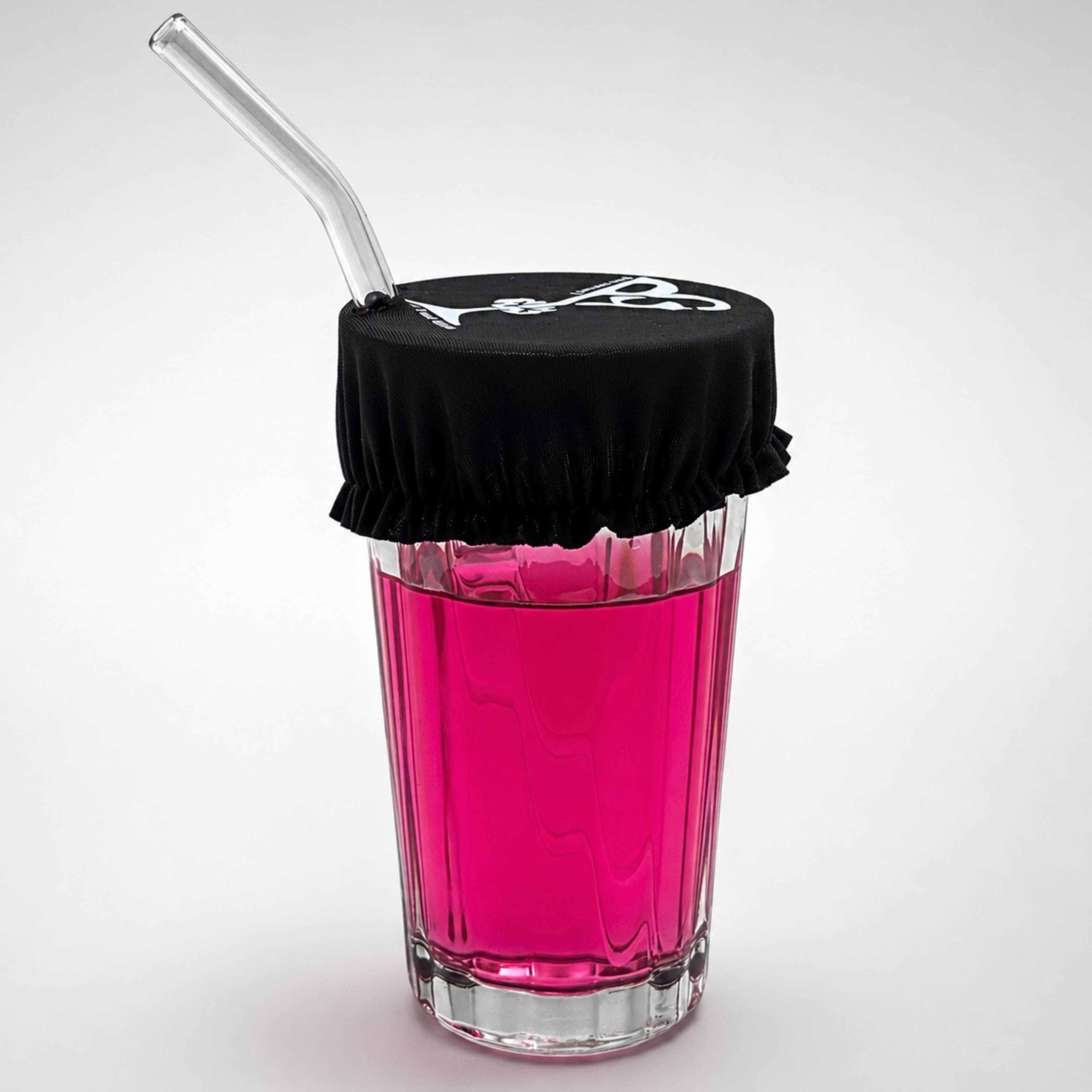 Gros plan sur le protège-verre porte-clés Protect Your Glass déployé sur un verre avec paille.