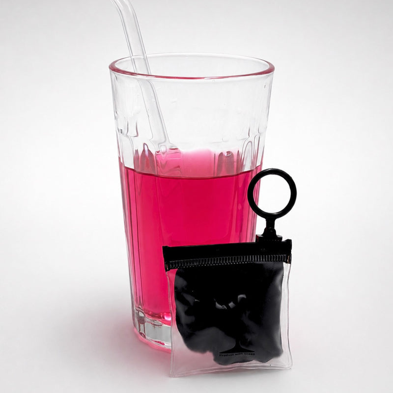 Protector de vaso Protect Your Glass guardado en su estuche llavero transparente junto a un vaso.