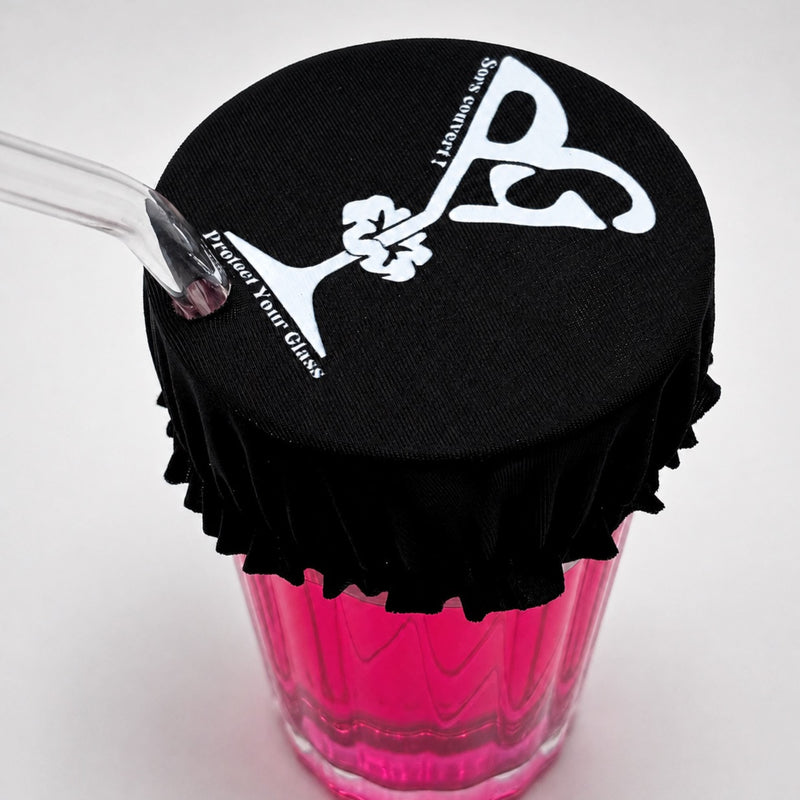 Protector de vaso con llavero Protect Your Glass desplegado sobre un vaso, con su estuche de almacenamiento al lado.